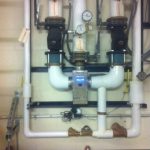 A wall-mounted water heater featuring various valves and gauges for monitoring and control.