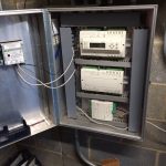 A metal cabinet housing various electrical equipment and wires, showcasing organized components for efficient power management.