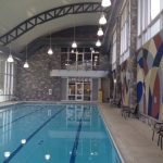 An indoor swimming pool featuring a large, vibrant mural adorning the wall, creating a serene atmosphere for swimmers.