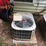 A technician is repairing an air conditioner, focused on the unit with tools in hand, ensuring optimal performance.